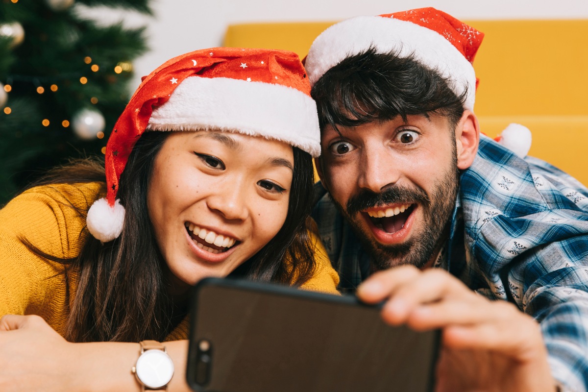 Couple avec bonnet de Père Noël surpris et heureux avec le tout nouveau forfait mobile de Sosh de 40 Go à 9.99€